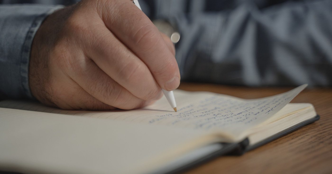 Eine Hand schreibt mit dem Stift in ein Notizbuch