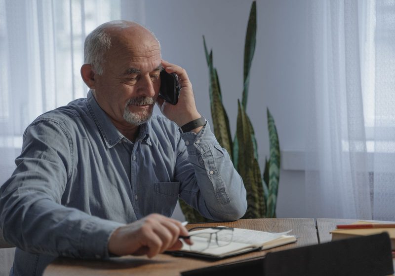 Ein Betriebsinhaber telefoniert an seinem Schreibtisch